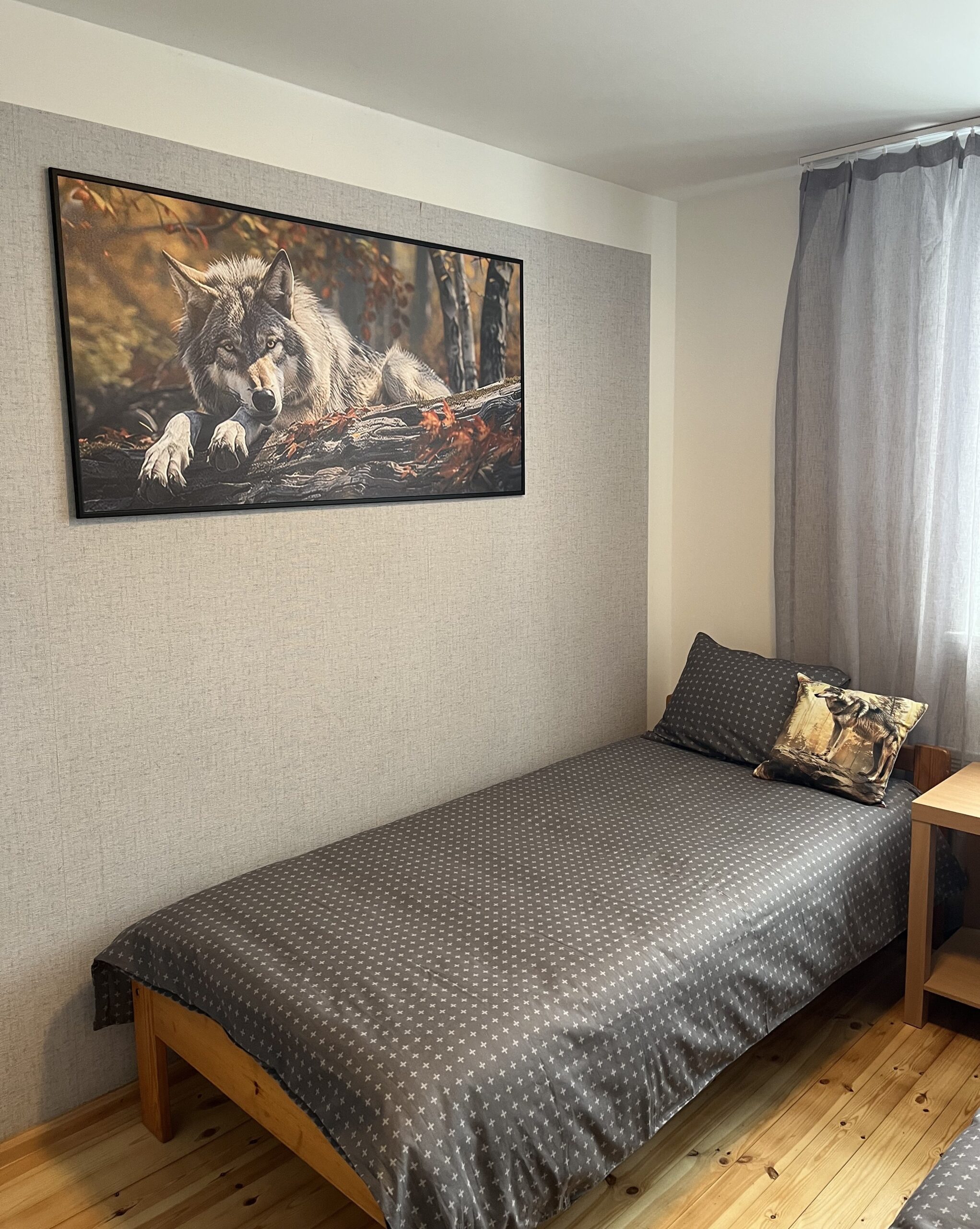 Hubane tuba HUNT Suurlahe Guesthouse'is Saaremaal – suur hundimaal seinal, voodi halli voodipesuga ja puitpõrand.