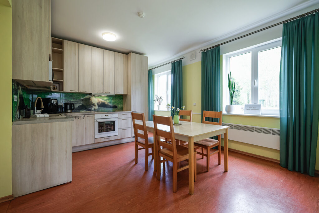 Suurlahe Guesthouse köögi ja söögiala heledate puidust kappide, laua, toolide ja suurte akendega.