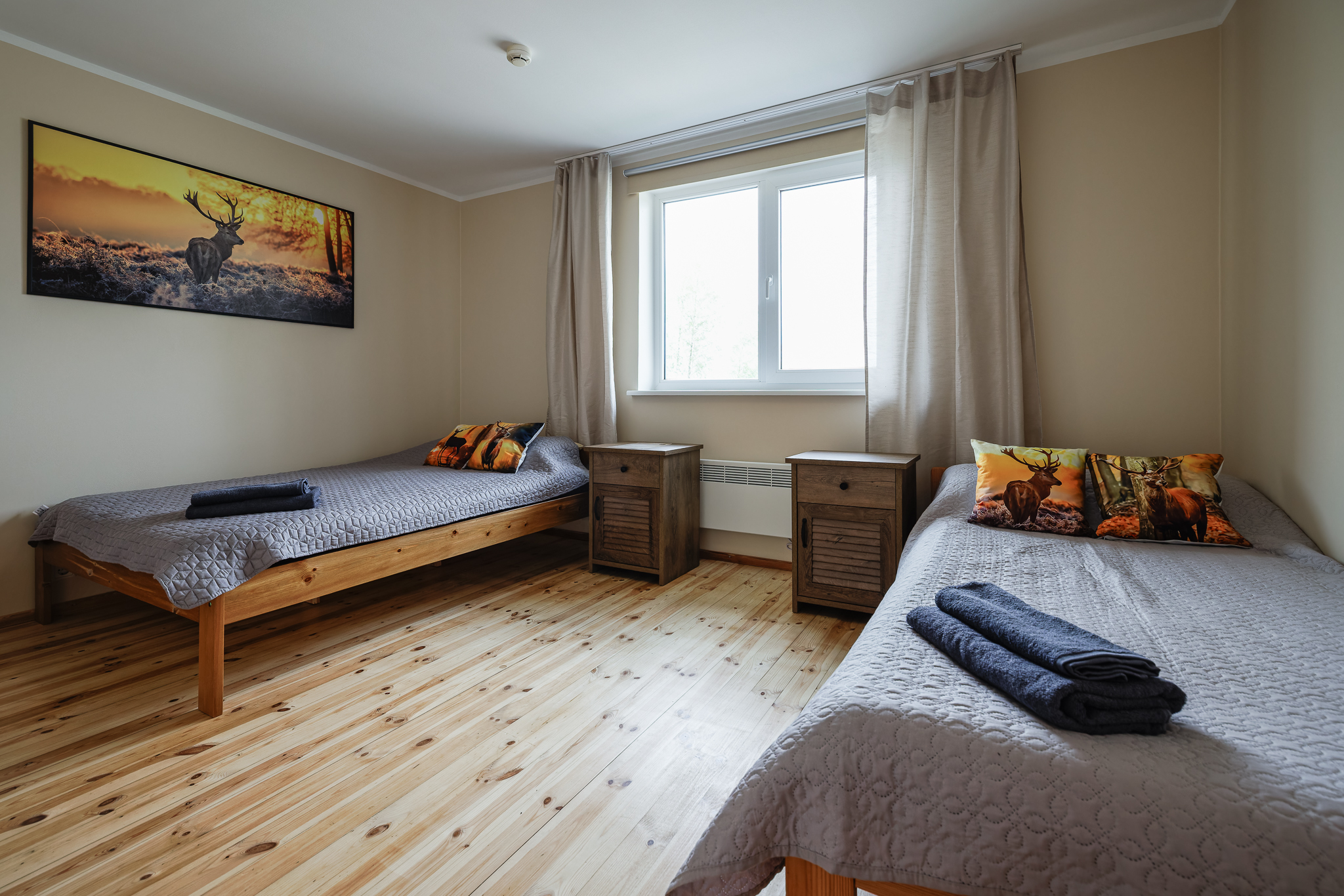 Kahe eraldi voodiga tuba Suurlahe Guesthouse majutuses, puidust põranda, öökappide, akna ja loodusest inspireeritud sisekujundusega.