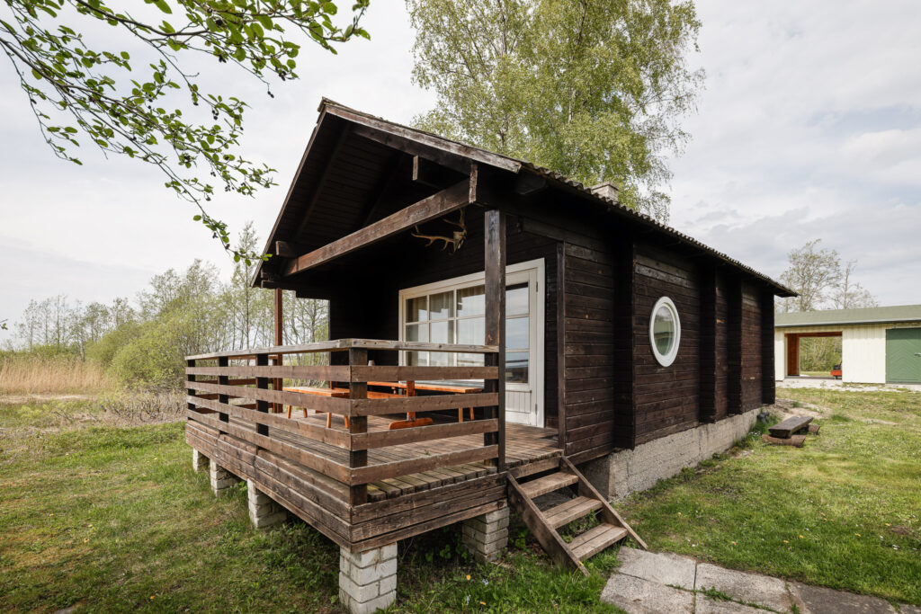 Tume puidust majake Suurlahe Guesthouse alal privaatse terrassi, istumisala ja loodusliku ümbrusega.