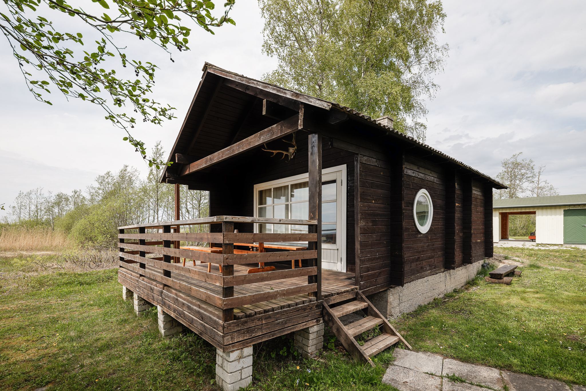 Tume puidust majake Suurlahe Guesthouse alal privaatse terrassi, istumisala ja loodusliku ümbrusega.